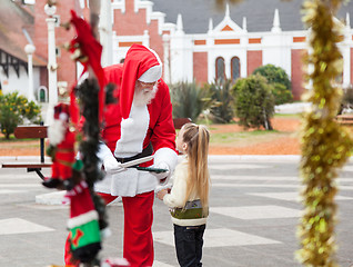 Image showing Santa Claus Offering Cookies To Girl