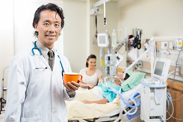 Image showing Doctor Holding Coffee Cup With Patient Resting On Bed