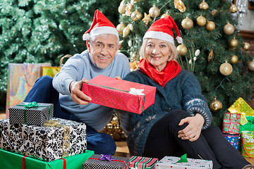 Image showing Portrait Of Senior Couple Offering Present In Christmas Store