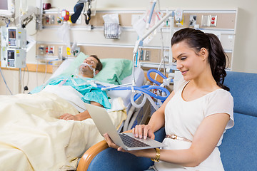 Image showing Woman Using Laptop While Sitting By Patient Resting In Bed