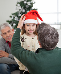 Image showing Father Adjusting Girl's Santa Hat