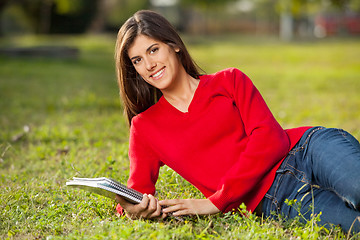 Image showing Female Student With Books Relaxing On Grass At Campus