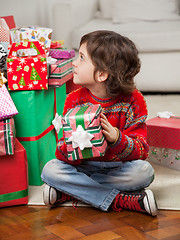 Image showing Boy Holding Christmas Gift While Sitting On Floor