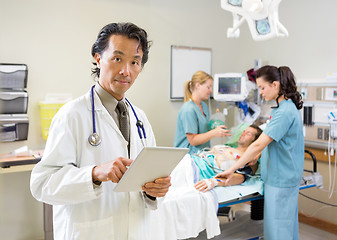 Image showing Doctor Using Digital Tablet While Nurses Treating Patient