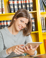 Image showing Woman With Digital Tablet Sitting Against Bookshelf In Library