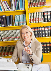 Image showing Confident Teacher With Books Sitting At Table In Library