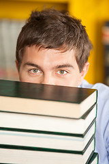 Image showing Student Peeking Over Piled Books In University Library