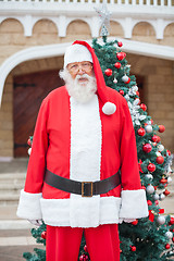 Image showing Santa Claus Standing Against Christmas Tree