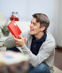 Image showing Smiling Man Looking At Christmas Gift