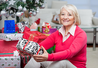 Image showing Senior Woman Sitting By Stack Of Christmas Presents