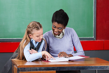 Image showing Teacher And Schoolgirl Reading Together At Desk