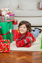 Image showing Happy Boy Lying Besides Stacked Christmas Gifts