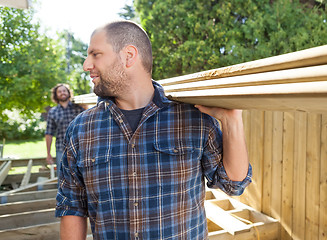 Image showing Carpenters Carrying Planks At Construction Site