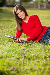Image showing Woman Holding Books While Relaxing On Grass At Campus