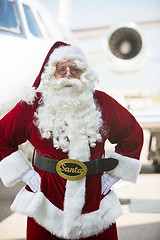 Image showing Santa Standing With Hands On Hip Against Private Jet