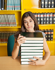 Image showing Confused Student With Stacked Books Sitting At Table In Library