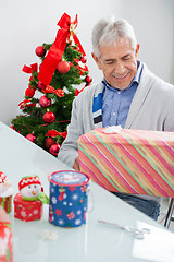 Image showing Man Looking At Wrapped Christmas Present