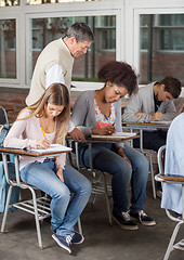 Image showing Students Writing Exam While Professor Supervising Them In Classr