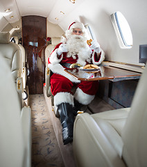 Image showing Santa Having Cookies And Milk In Private Jet