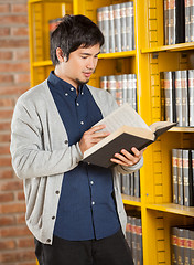 Image showing Student Reading Book By Shelf In Library