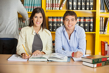 Image showing College Students With Books Sitting At Table In Library