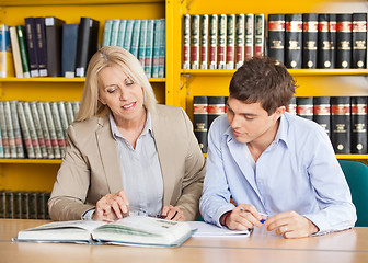 Image showing Teacher Explaining Student While Sitting At Table In Library