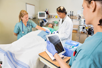 Image showing Nurse Holding Digital Tablet While Colleague And Doctor Operatin