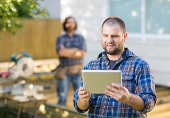 Image showing Carpenter Using Digital Tablet With Coworker Standing In Backgro