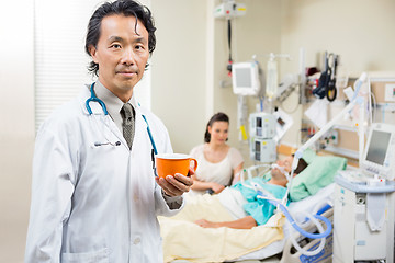 Image showing Doctor Holding Coffee Cup With Patient Resting In Hospital