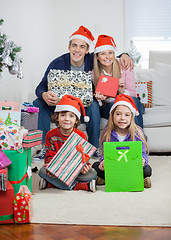 Image showing Family In Santa Hats Holding Christmas Gifts