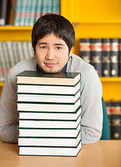 Image showing Student Resting Chin On Stacked Books At Table In Library