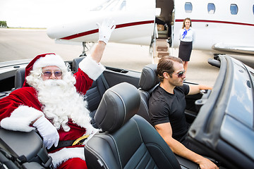 Image showing Santa Waving Hand While Chauffeur Driving Convertible Against Pr