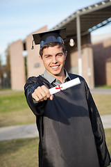 Image showing Man In Graduation Gown Showing Diploma On University Campus