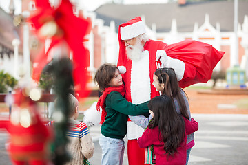 Image showing Children Embracing Santa Claus