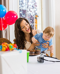 Image showing Mother Holding Boy With Messy Hands Covered With Cake Icing