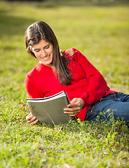 Image showing Woman Reading Book While Relaxing On Grass At Campus