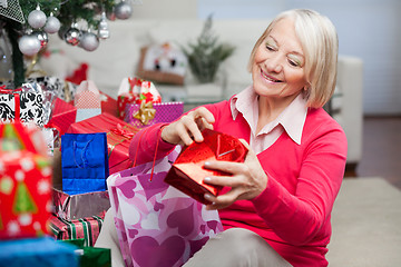 Image showing Woman Looking In Bag While Sitting By Christmas Gifts
