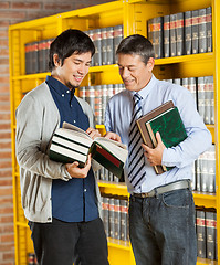 Image showing Librarian Holding Books While Explaining Student In Library