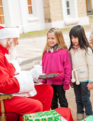 Image showing Santa Claus With Biscuits And Milk Looking At Children