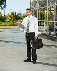 Image showing Confident Teacher With Laptop Bag And Books Standing On College