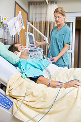 Image showing Nurse Examining Patient Lying On Bed