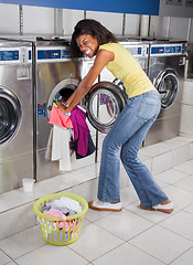 Image showing Woman Pushing Clothes In Washing Machine