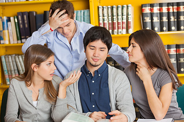 Image showing Worried Students With Book Sitting In Library