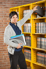 Image showing Student Taking Book From Shelf In College Library