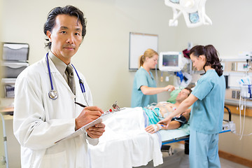 Image showing Doctor Holding Clipboard With Nurses Examining Patient