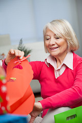 Image showing Smiling Senior Woman Looking In Bag At Home