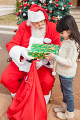 Image showing Girl Receiving Present Against Christmas Tree