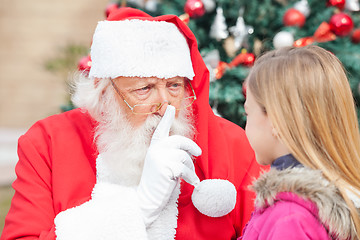 Image showing Santa Claus Gesturing Finger On Lips While Looking At Girl