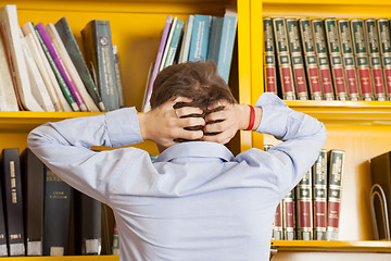 Image showing Student Pulling Hair Against Bookshelf In University Library