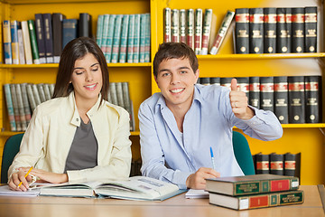 Image showing Student Gesturing Thumbsup While Friend Reading Book In Library